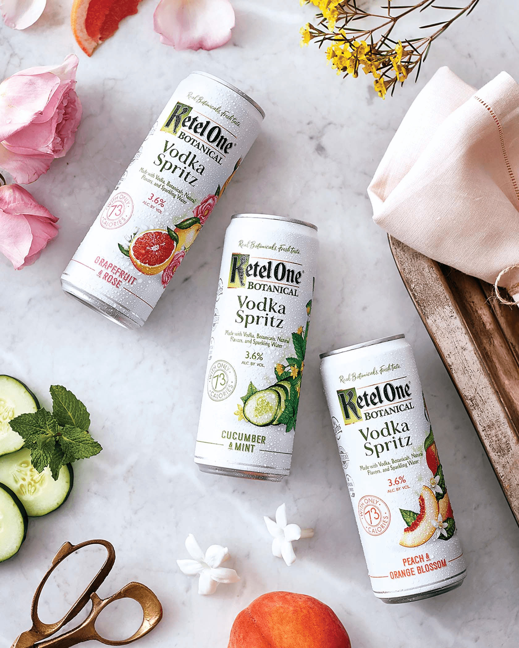 Botanical vodka spritz cans arranged with fresh fruit and flowers